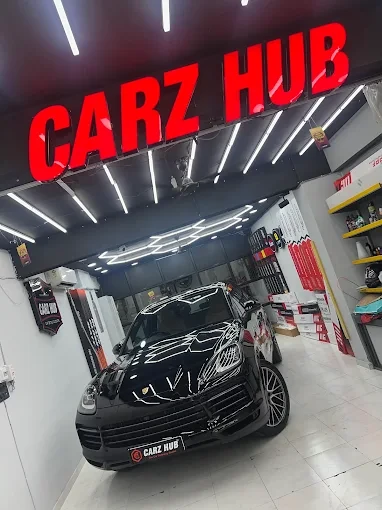 Black Porsche inside the Carz Hub studio beneath the red Carz Hub sign